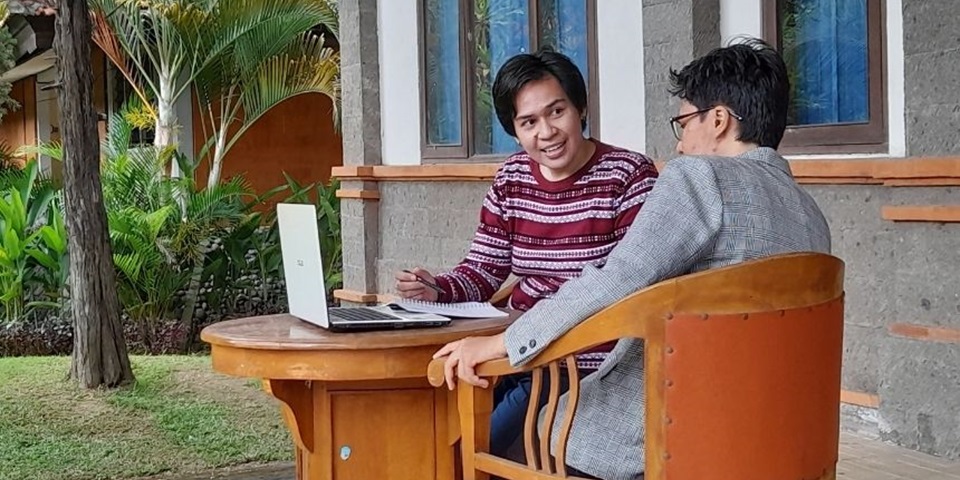 Student sits outside at a table with their laptop