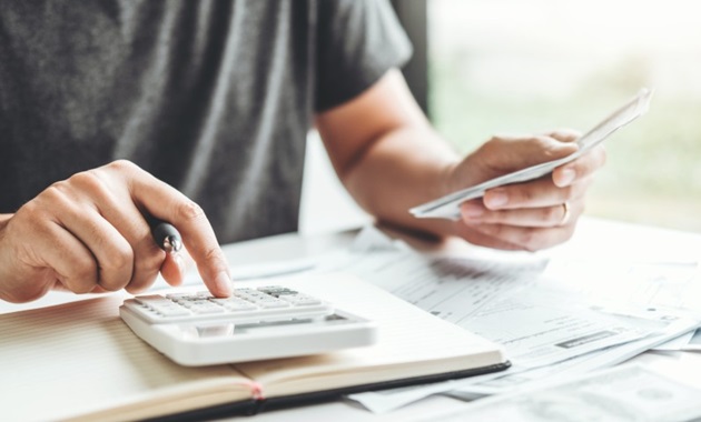 Person using a calculator, whilst holding a pen